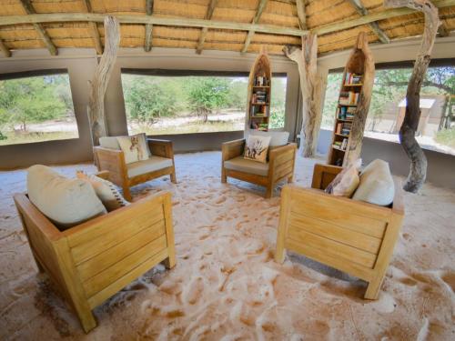 a room with couches and chairs in the sand at Leopard Plains in Motopi
