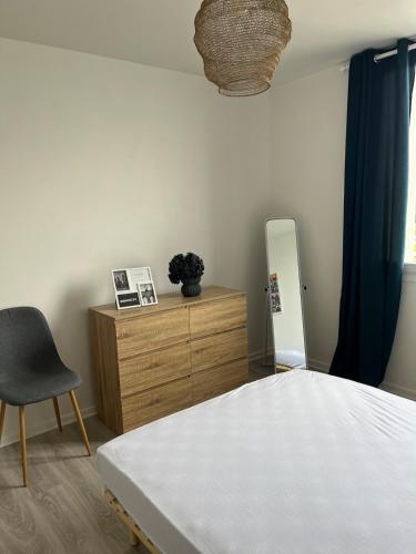 une chambre avec un lit, une chaise et un miroir dans l'établissement T2 Anglet City Center, à La Celle-sous-Gouzon