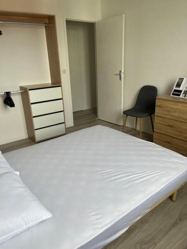 une chambre avec un grand lit blanc et une chaise dans l'établissement T2 Anglet City Center, à La Celle-sous-Gouzon