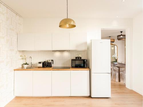  La cuisine est équipée de placards blancs et d'un réfrigérateur. dans l'établissement Merveil - Family Suite - Louvre - Sainte Anne, à Paris