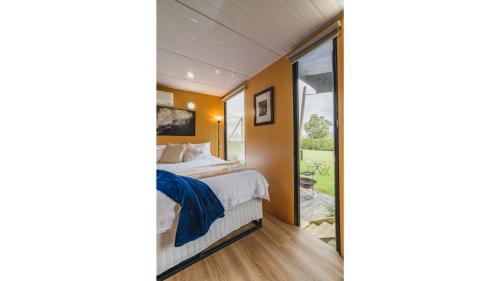 a bedroom with a bed and a large window at The Junction by Tiny Away in Yarra Junction