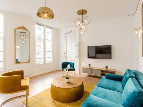 un salon avec un canapé bleu et des chaises dans l'établissement Merveil - Family Suite - Louvre - Sainte Anne, à Paris