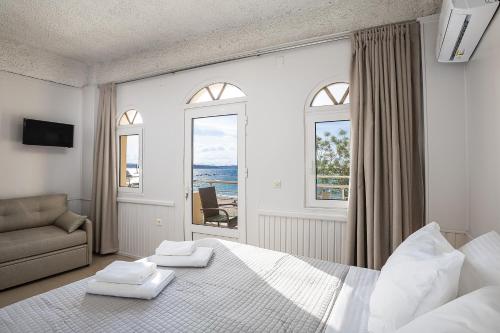 a white bedroom with a large bed and a window at Neachora Beachfront Suites in Chania Town
