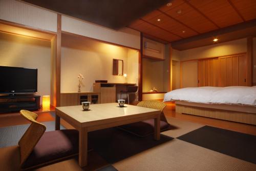 a room with a bed and a table and a bedroom at Hotel Kunitomi Suisennkaku in Itoigawa