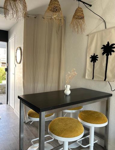 une salle à manger avec une table noire et deux tabourets dans l'établissement Ile tudy Bord de plage et farniente en terrasse Appt classé 3 étoiles, à l'Île-Tudy