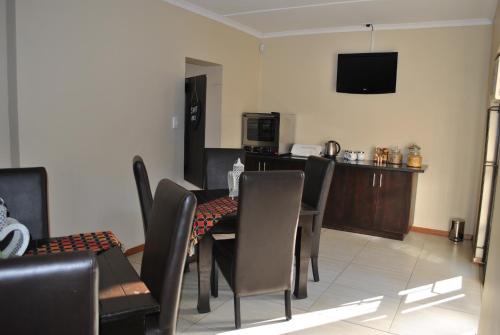 a dining room with a table and chairs and a television at Amaris Guesthouse in Lichtenburg