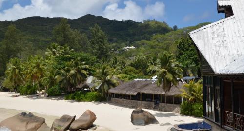 a resort on a beach with palm trees and a mountain at Villa Chez Batista in Takamaka