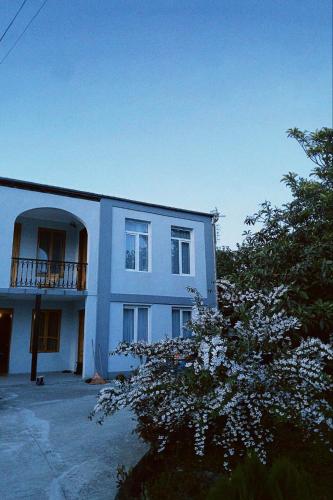 Un edificio blanco con un balcón y un árbol. en Kisa, en Martvili