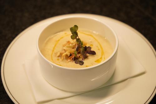 a white bowl of soup on a white plate at Hotel Watermolen Le Mirage in Kasterlee