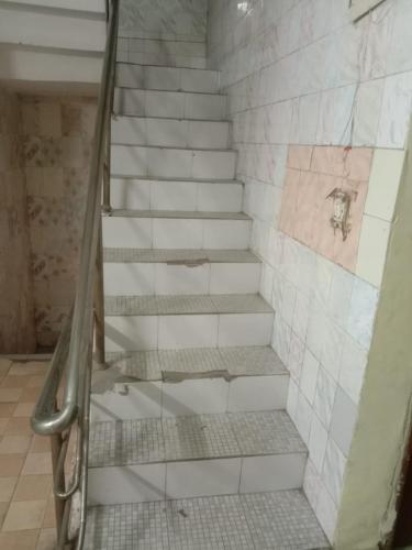 a set of stairs in a bathroom with white tiles at AGRA HOTEL VIREN SOFYTEL - Near Taj Mahal And Park# - Free Wi-fi And Parking Facilities - A Premium Hotel In Agra in Agra