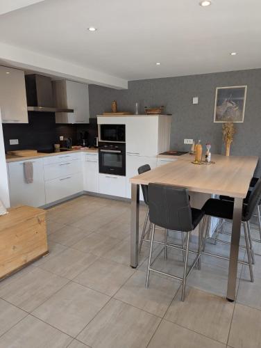 une cuisine avec une table et des chaises en bois dans l'établissement Aux balcons de la vallée, à Soultzeren