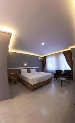 a bedroom with a large bed and two chairs at Altayhan Otel in Amasya