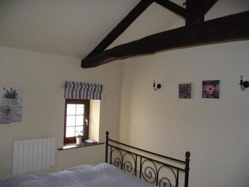 une chambre avec un lit et une fenêtre dans l'établissement Les Volets Bleus, à Saint-Saviol