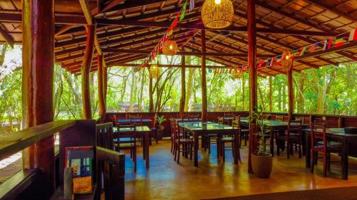 ein Restaurant mit Tischen und Stühlen in einem Wald in der Unterkunft Jungle Host Hostel And Tree House in Sigiriya