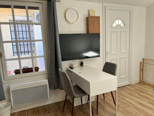 un bureau blanc avec deux chaises et une horloge sur un mur dans l'établissement Petite maison de ville Matabiau Jean Jaurès, à Toulouse