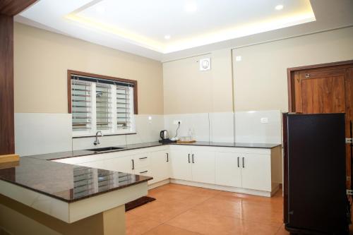 una cucina con mobili bianchi e un piano di lavoro nero di Skyscape Resort a Kaniyāmbetta