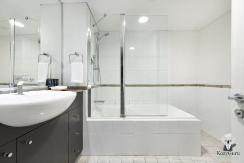 Un baño blanco con lavabo y ducha. en KozyGuru | Sydney CBD | Best Location Studio, en Sídney