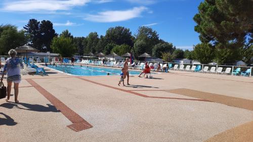 un groupe de personnes debout autour d'une piscine dans l'établissement Mobil home charmant EMPL 521, aux Mathes