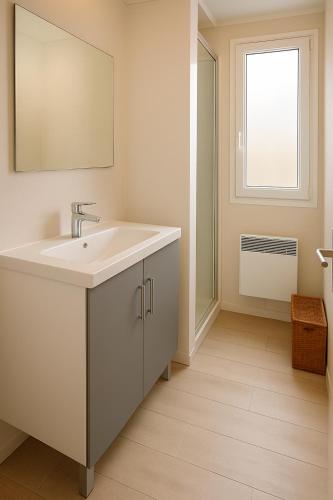 une salle de bain avec un lavabo blanc et une fenêtre dans l'établissement Mobil-home 6 pers, tout confort Clim, piscine & animations, à Agde