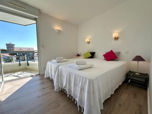 Cette chambre comprend un lit avec des draps blancs et une grande fenêtre. dans l'établissement Elegant T3 vue mer, à Capbreton