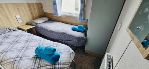 two beds in a small room with blue cushions at Caravan-Blackpool-FamilyFriendly-Activities in Fleetwood