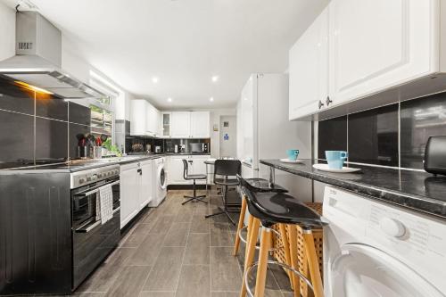 a kitchen with white cabinets and black appliances at Lord’s Guesthouse - Room 3 in London