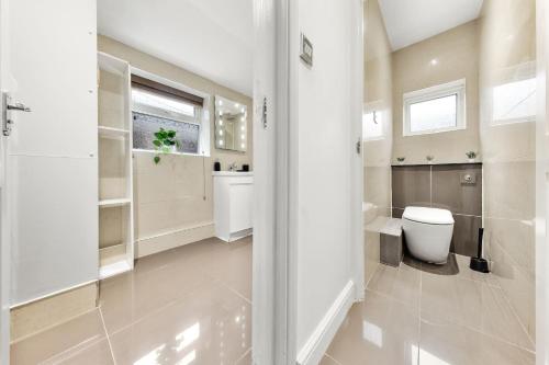 a white bathroom with a toilet and a sink at Lord’s Guesthouse - Room 3 in London