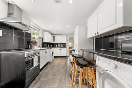 a kitchen with white cabinets and black appliances at Lord’s Guesthouse - Room 3 in London