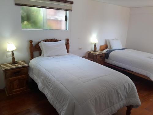 two beds in a room with two lamps on tables at Casa de la Luna in Comunidad Yumani