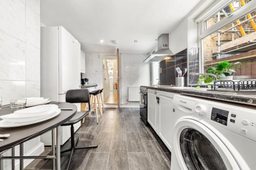 a kitchen with a washer and dryer and a table at Lord’s Guesthouse - Room 3 in London