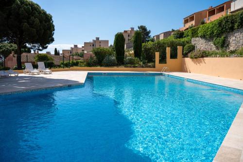 une piscine avec de l'eau bleue dans un immeuble dans l'établissement Alora - Superbe Studio Vue Mer Climatisé avec Piscine, à Cavalaire-sur-Mer