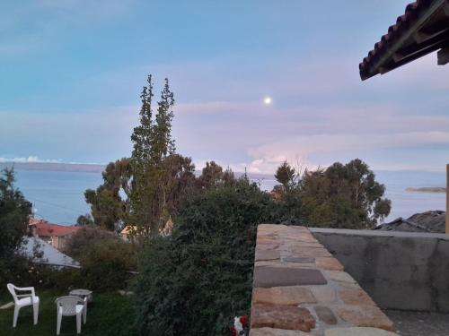 a stone wall with two chairs and a view of the water at Casa de la Luna in Comunidad Yumani