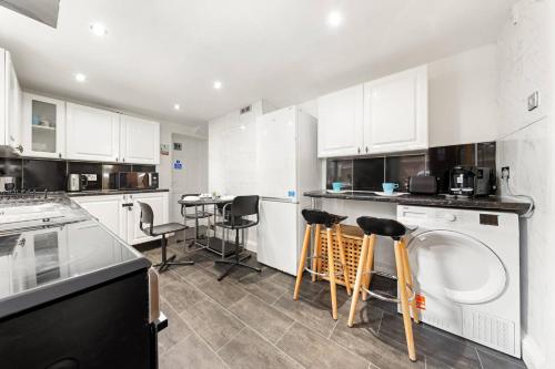 a kitchen with white cabinets and a washing machine at Lord's Guesthouse - Room 4 in London