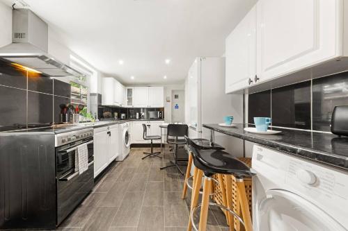 a kitchen with white cabinets and black appliances at Quadruple - King Room in London