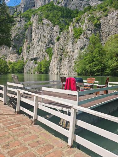 a wooden dock with chairs and a boat on the water at Ambijent house in Železnička Stanica Ovčar Banja