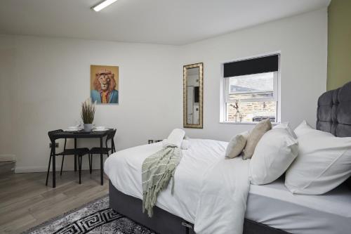 a white bedroom with a bed and a table at Hayy Vibrant Studios Queensgate in Huddersfield