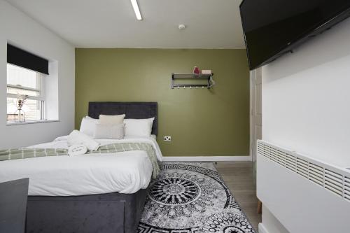 two beds in a room with green walls at Hayy Vibrant Studios Queensgate in Huddersfield