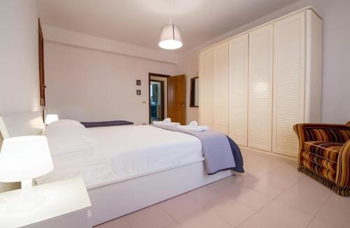 a white bedroom with a large bed and a chair at Vista Mare Lido Avola in Avola