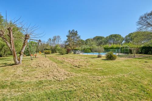 un parc vide avec une balançoire dans une cour dans l'établissement CAPE - maison avec piscine et jacuzzi, à Thénac