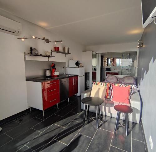 une cuisine avec des armoires rouges et une table et des chaises dans l'établissement Studio 559, Port Nature 5 au village naturiste, au Cap d'Agde