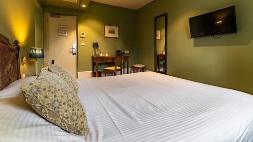 a bedroom with a white bed with a television on the wall at Domaine de Saulon in Saulon-la-Rue