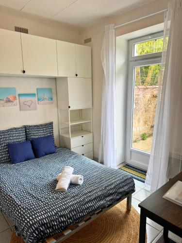 une chambre avec un lit avec des oreillers bleus et une fenêtre dans l'établissement Nid Bleu - Central - Wifi - Équipé, à Dax