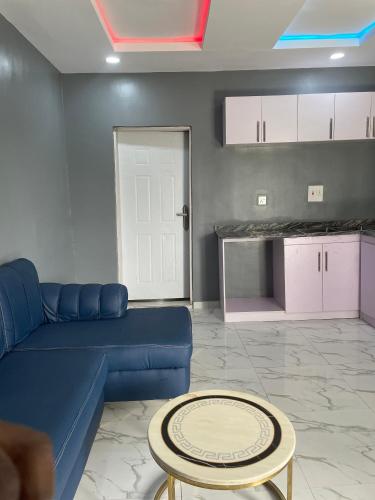 a living room with a blue couch and a table at Umbrella Properties hotels and apartments - Moniya in Ibadan