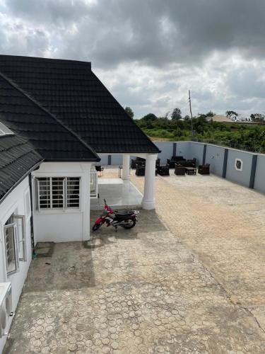 a house with a patio with a motorcycle parked in front at Umbrella Properties hotels and apartments - Moniya in Ibadan