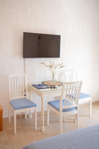 a table with two chairs and a tv on a wall at Amatu Villa (Athena) in Xerokampos