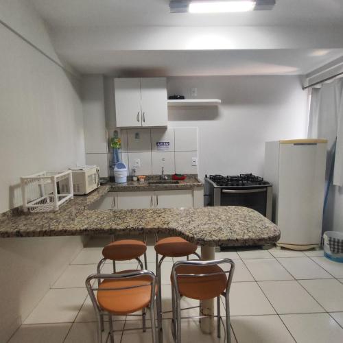 a kitchen with a counter and four stools at Golden Dolphin Grand Hotel piscinas 24 hs MP in Caldas Novas