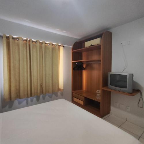 a bedroom with a bed and a tv on a shelf at Golden Dolphin Grand Hotel piscinas 24 hs MP in Caldas Novas