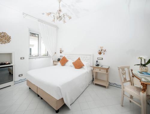 a white bedroom with a large bed and a table at Hotel Quisisana in Capri