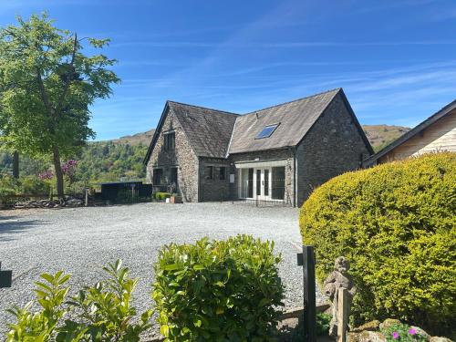 a stone house with a gravel driveway at Bridge House Hotel & Silver Howe View Cottage in Grasmere