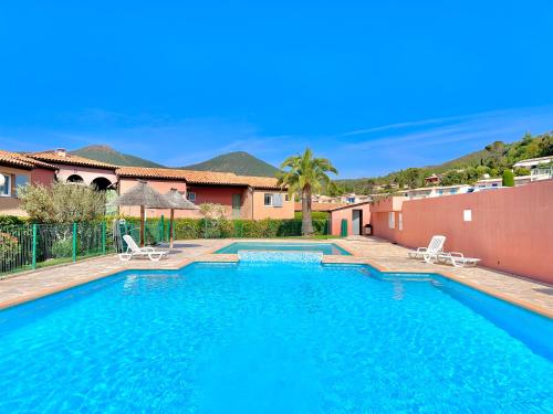 une piscine avec deux chaises et une maison dans l'établissement Petite maison pour 6 - jardin clim piscine parking, à Théoule-sur-Mer